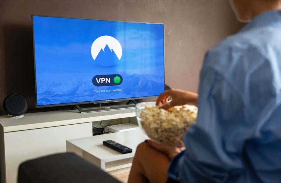 uomo seduto sul divano mentre è collegato a NordVPN sul suo televisore grazie ad un account acquistato con un coupon NordVPN