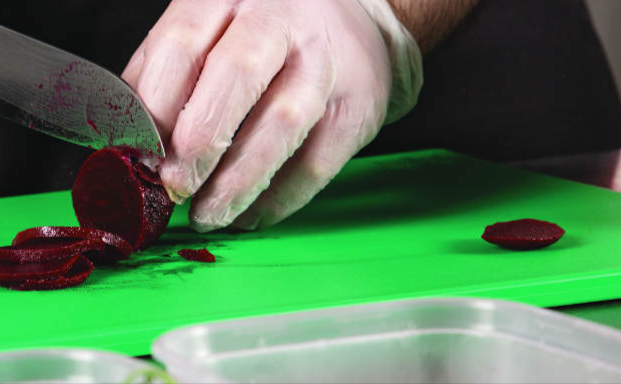 Beetroot being sliced on a green chopping board