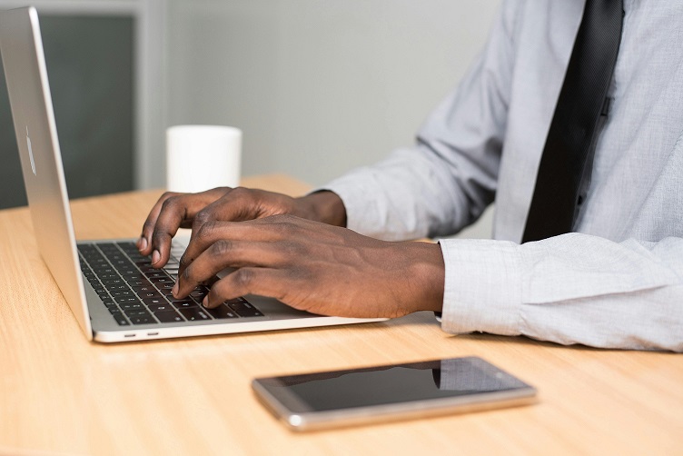 image showing hands hovering over laptop keys.