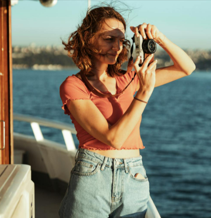 A woman with brunette hair taking a picture on a cruise booked on Cruise118