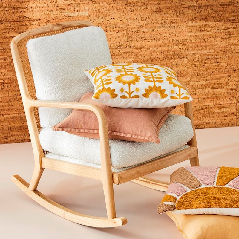rocking chair with two pillows resting on it and two pillows on the floor in front of it