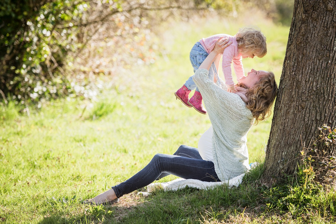 madre sosteniendo a su hija en un parque de día y césped verde