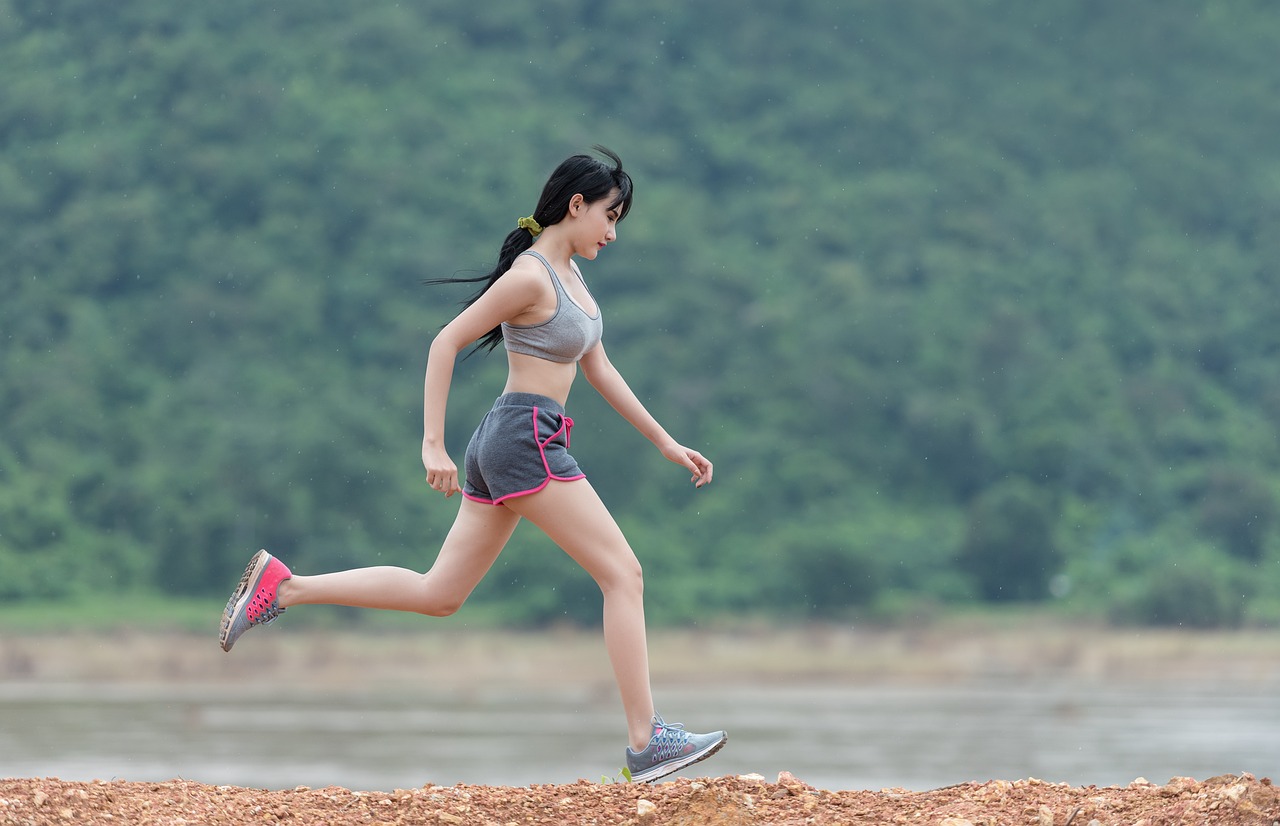 Sporcu şortu ve koşu yol spor ayakkabı modeli giyen genç kadın açık alanda hızla koşuyor