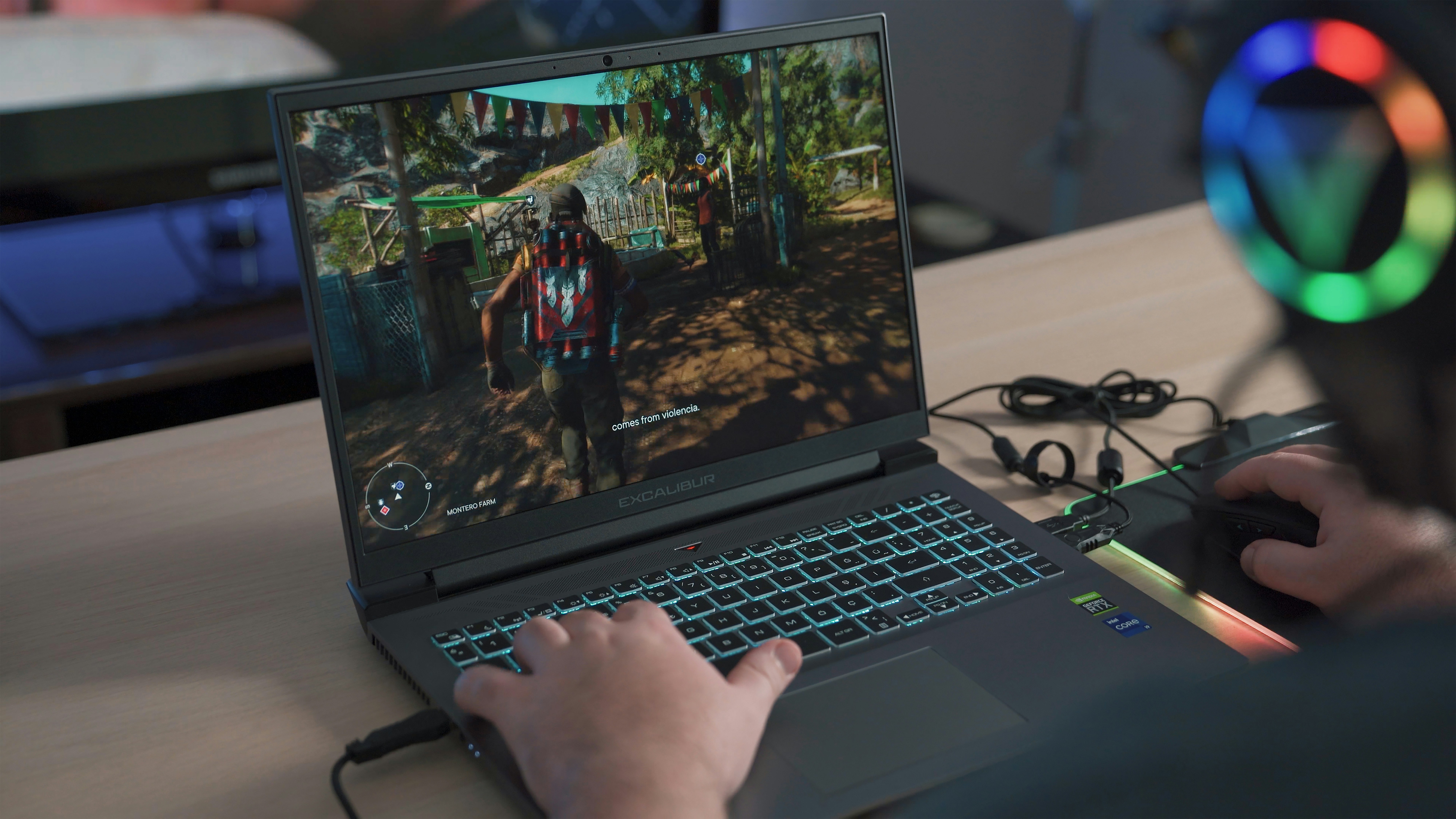 man sitting while looking over to his laptop palying games