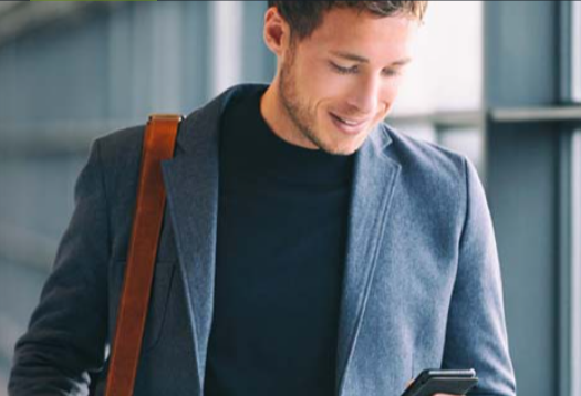 A man looking into a phone in his hand and smiling
