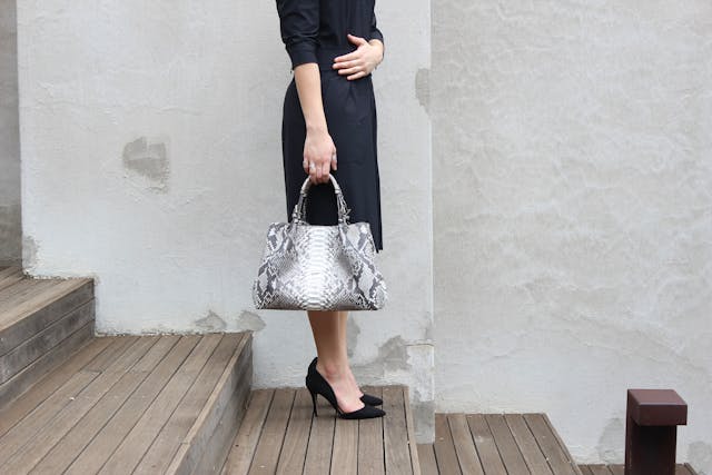 Autumn capsule wardrobe: A woman wearing a dress and heels while holding a handbag