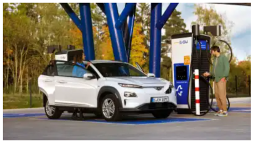 Ein Mann, der gerade sein weißes Elektroauto bei einer E-Ladestation auflädt