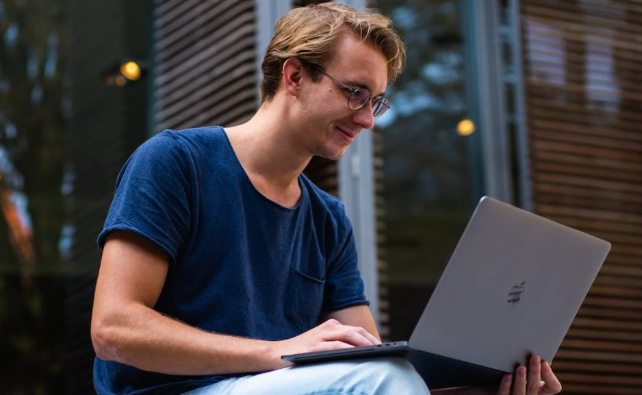Male student viewing Travelodge UK voucher codes on his laptop, he is smiling about this