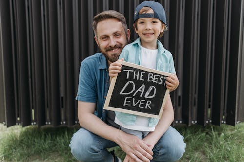 A father and son holding a sign saying Happy Fathers Day