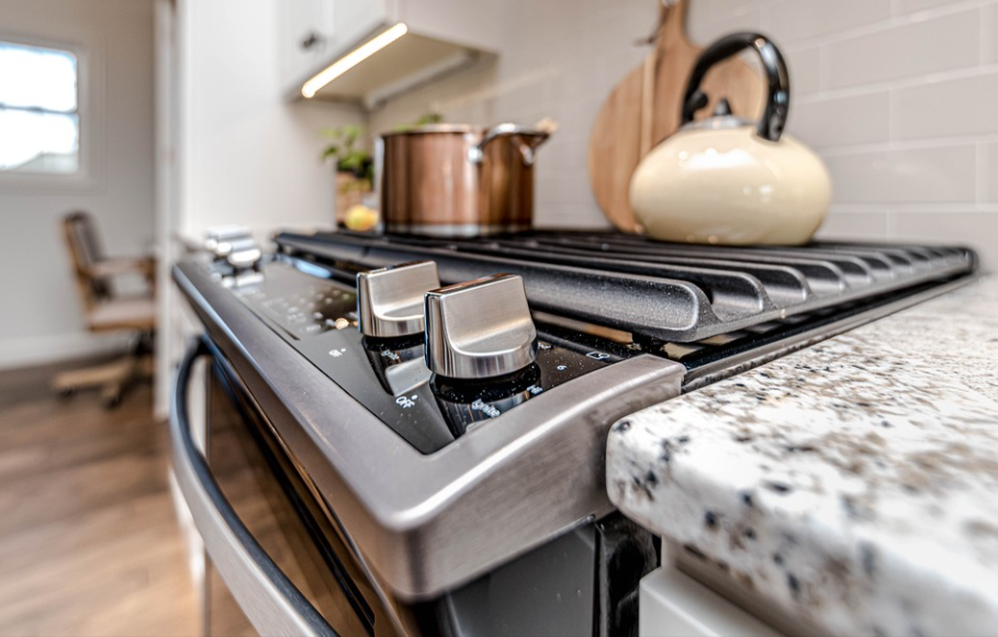 Silver kitchen stove with a pot and kettle on it