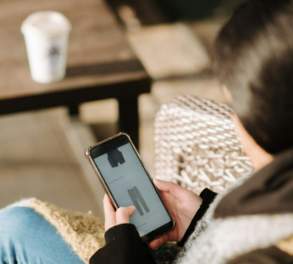 Young woman choosing clothes on the FLANNELS app sitting in an armchair in a cafeteria