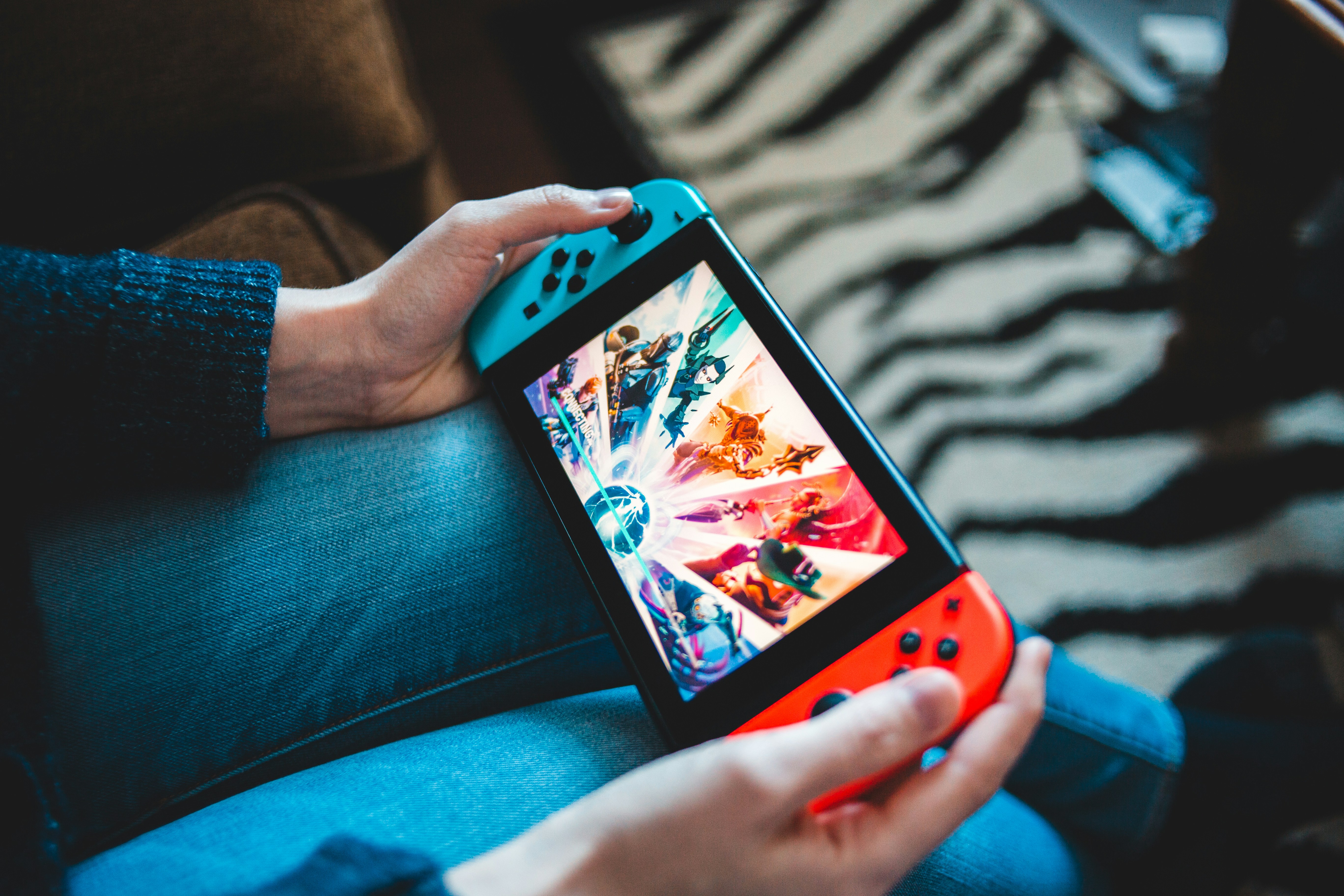 a persn holding a gaming console with screen playing a game
