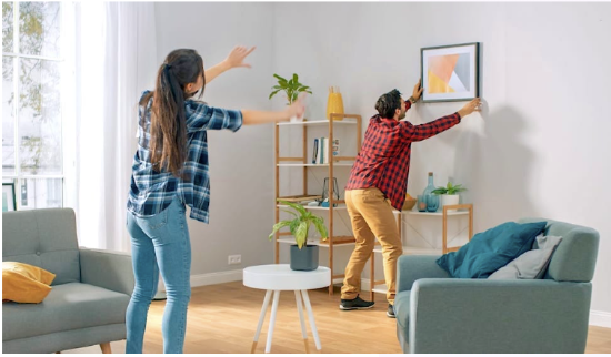 A couple hanging their picture frame on their lounge wall
