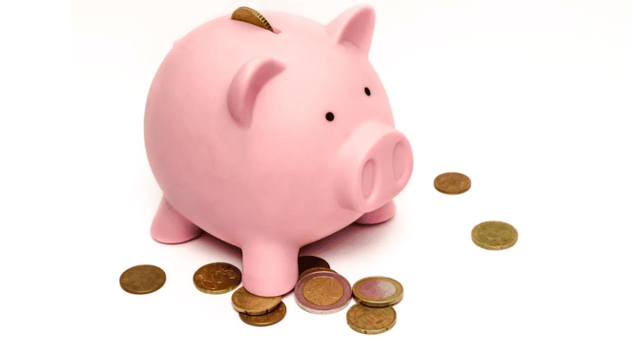 A pink piggy bank with coins on a white background