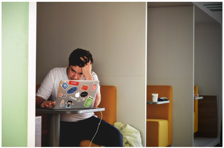 A male student scrolling through his laptop for a DV8 discount code to shop with
