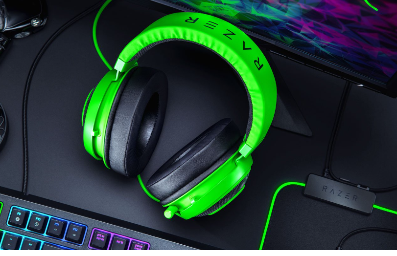 Razer kraken green gaming headset between a desktop and a keyboard on a black desk