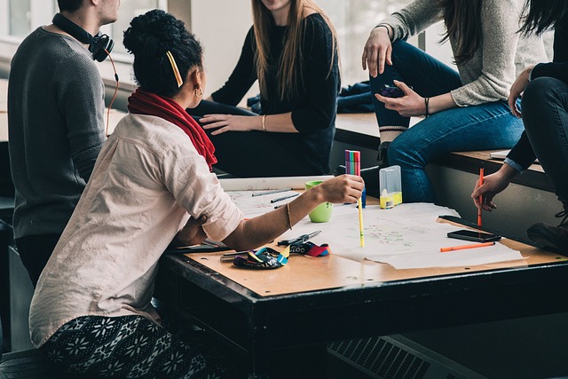 A group of people sitting around a table having a discussion with pens in their hands.