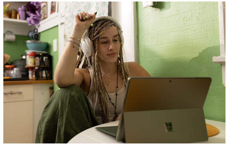 A female student with headphones on, scrolling on her laptop for a Not On The High Street promo