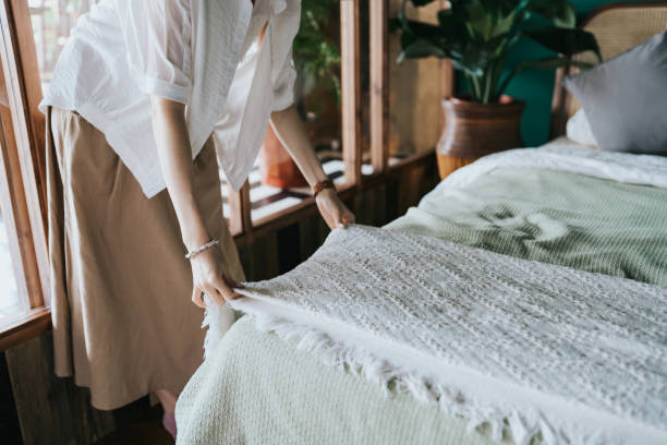 une dame dresse un lit situé dans une chambre avec dela literie disponible chez Home Beddings & Curtains avec un code de réduction  Home Beddings & Curtains
