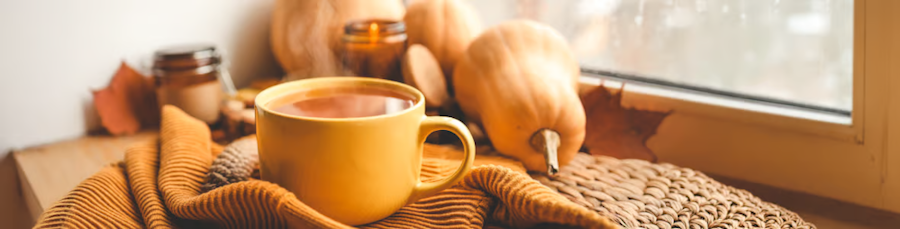 Eine volle Tasse auf einer Decke neben Gemüse vor einem Fenster