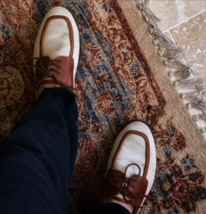 Brown and cream Grenson vintage loafers on a colourful oriental rug indoors.