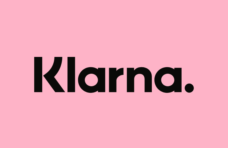Ein pinkes Bild mit dem Klarna-Logo in schwarzer Aufschrift darauf