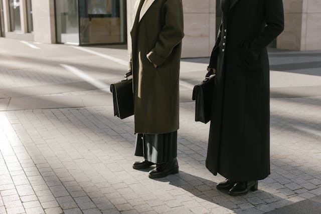 Two businesswomen wearing coats from an autumn capsule wardrobe