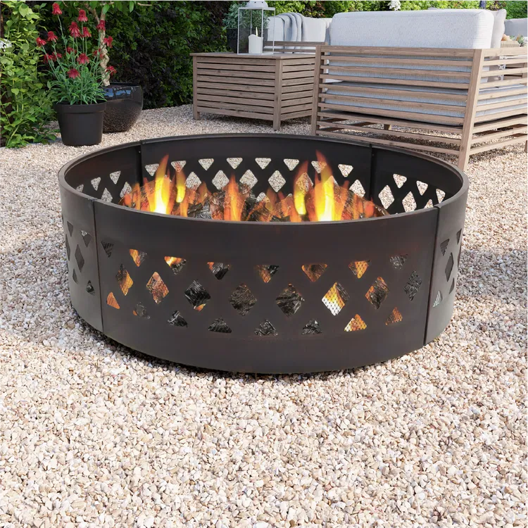 A round metal bonfire pit in a garden with seats and flowers in the background