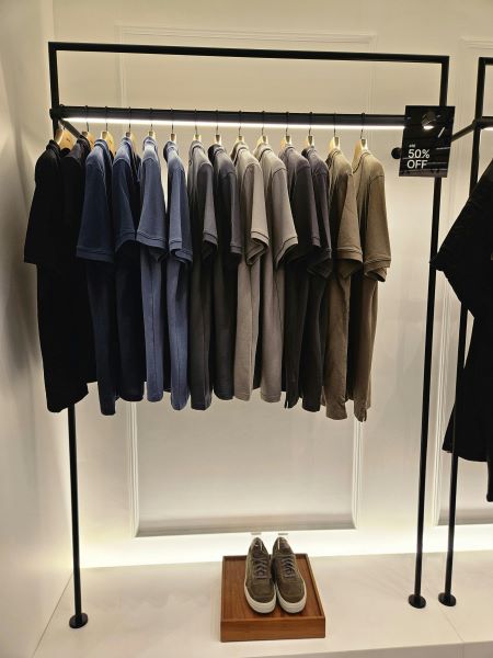 A clothing rack with a range of polo shirts and pair of shoes below