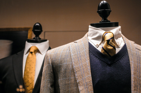 Two elegant 3-piece suits displayed on mannequins in a store