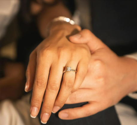 Close up of a couple holding hands and woman showing her ring