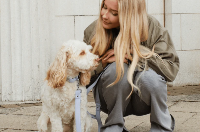 A woman crouching beside a white and brown dog