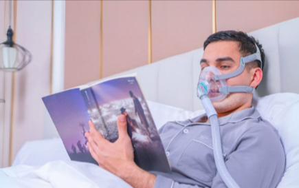 Man wearing a Intus Healthcare CPAP mask bundle while reading in bed