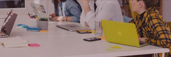 A group of people sitting around the table with their laptops open