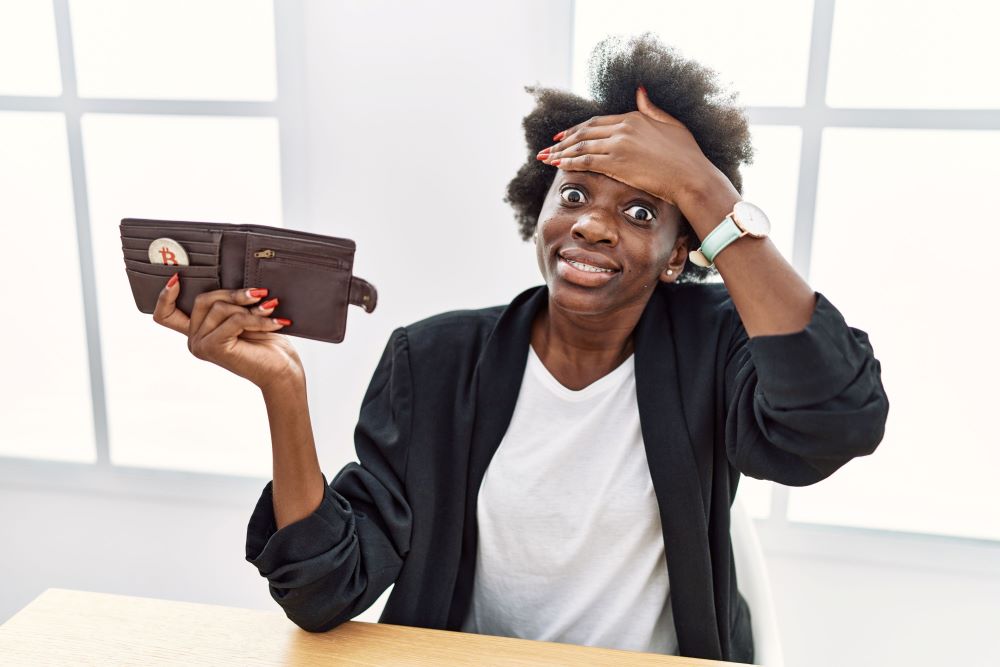 african-young-woman-holding-wallet-with-virtual-currency-bitcoin-stressed-frustrated-with-hand-head-surprised-angry-face