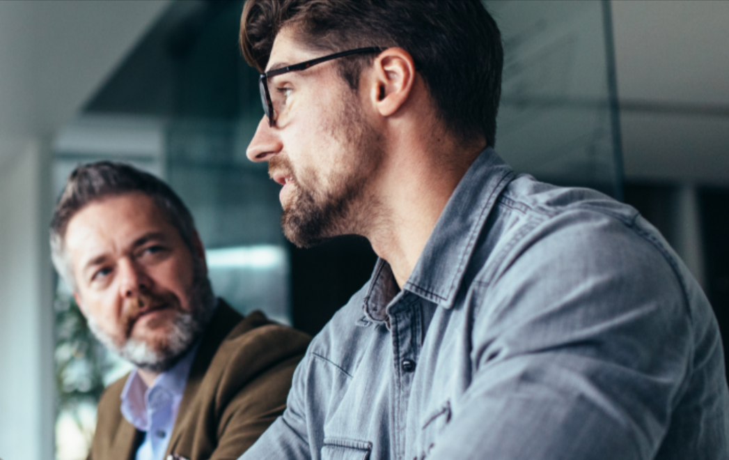 Two men sitting and seemingly having a conversation in an office set up