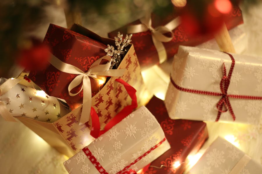 Red, gold, and white christmas gifts that has a blurry background of a tree