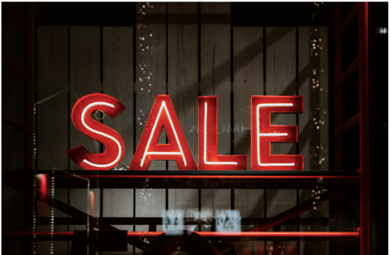 A red and white neon sale sign showing through a shop window