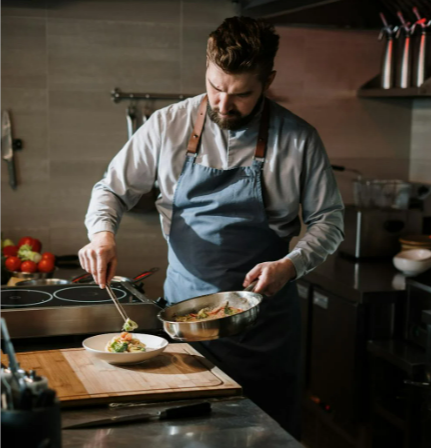 Man in white long sleeve shirt holding stainless steel cooking pot while in a kitchen with equipment from Currys Business