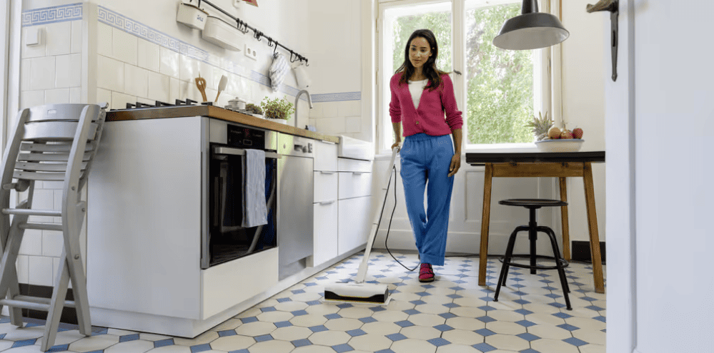 A woman using a Kärcher steam mopper to clean her kitchen floor