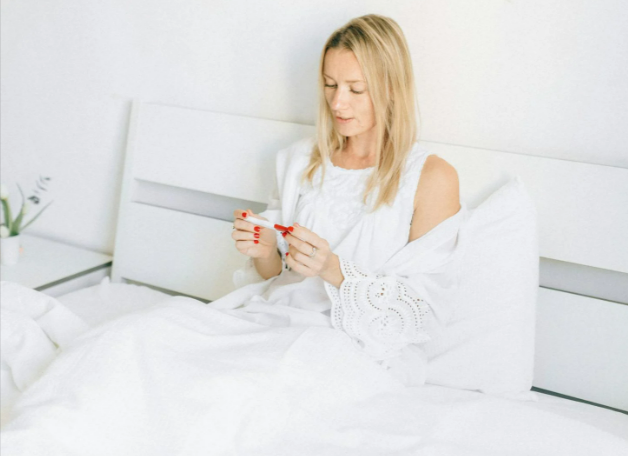 Woman in white tank top holding a test
