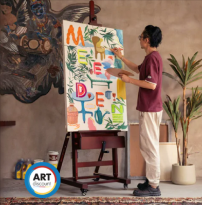 A man painting on a canvas which is propped up on an easel