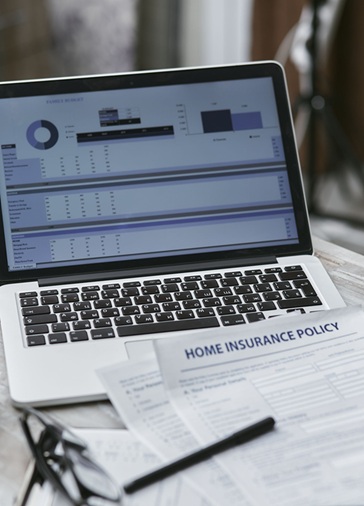 image showing a laptop and a form with the words "HOME INSURANCE POLICY" on it
