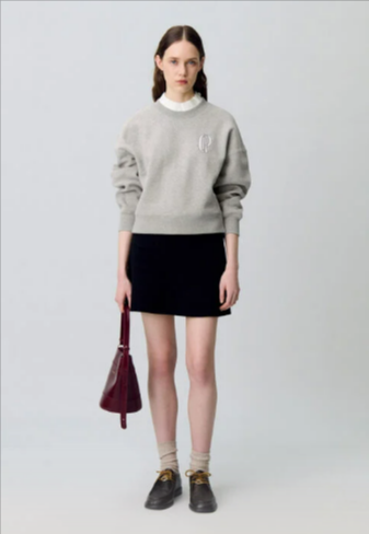 A lady wearing a grey sweatshirt from Claudie Pierlot bought using luxury fashion deals