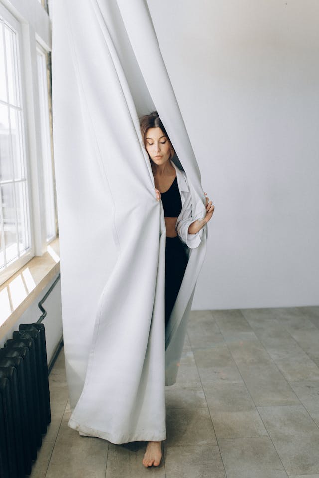 Curtains and blinds: A woman wrapping herself in white curtains