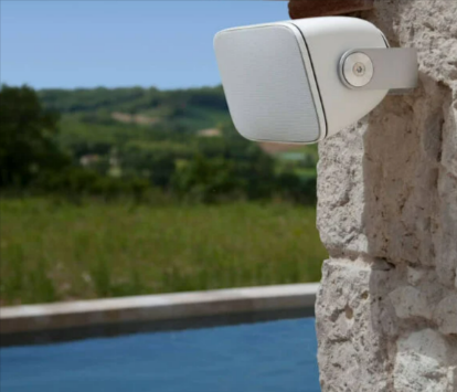 The Bowers & Wilkins white AM-1 outdoor speaker mounted on a house