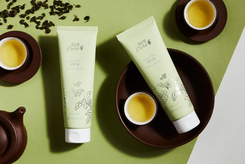 Zwei gleiche Sonnenschutzlotion von 100% Pure mit einigen Schalen und Tassen