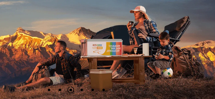 Eine Familie beim Campen mit einer Batterie von Redodo auf dem Tisch