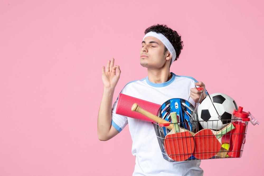 front-view-young-male-sport-clothes-with-basket-full-sport-things-pink-wall