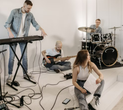 A lively group of young musicians rehearsing in a modern indoor studio setting with equipment from Gear4music.